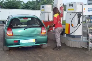 A gas station attendant is filling a car's tank at a service station in Abidjan.