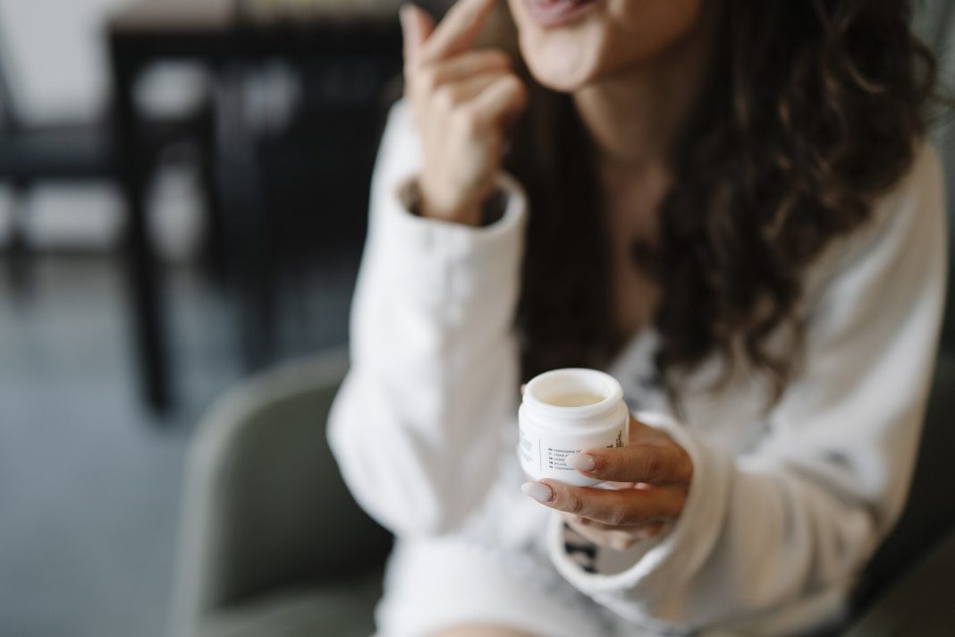 Femme appliquant une crème hydratante pendant une routine de soin du visage