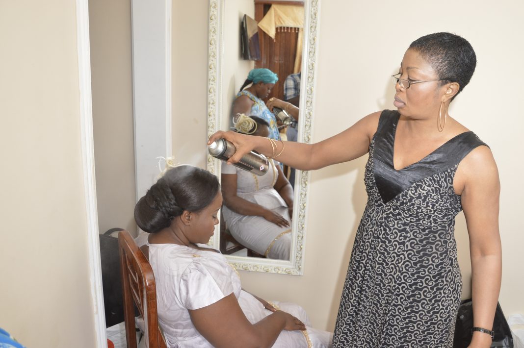 Coiffeuse appliquant un spray capillaire dans un salon à Douala