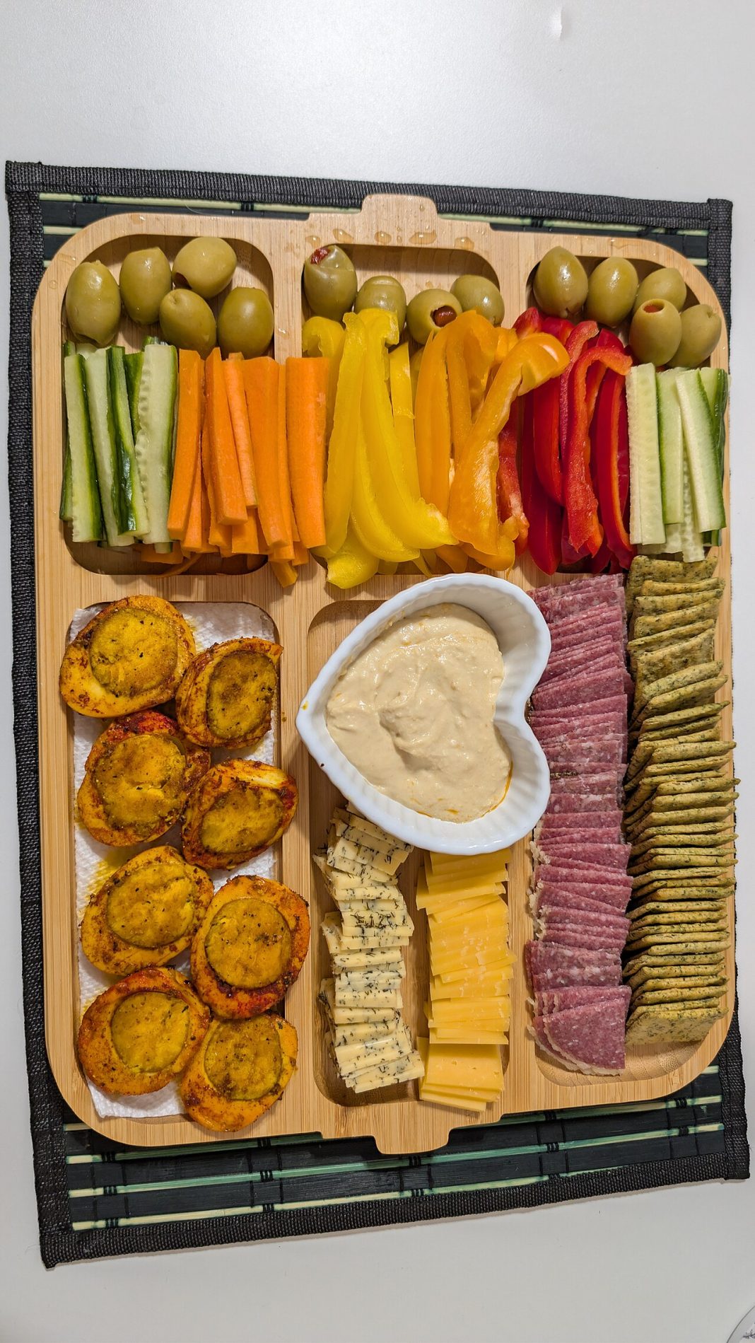 Plateau de grignotage avec légumes, crackers, fromage, œuf, olives et houmous