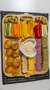 Plateau de grignotage avec légumes, crackers, fromage, œuf, olives et houmous