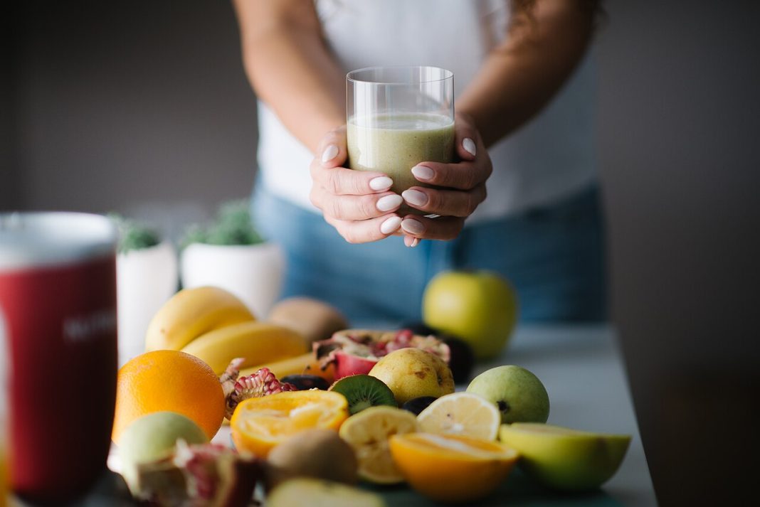 Un verre de smoothie vert entouré de fruits frais