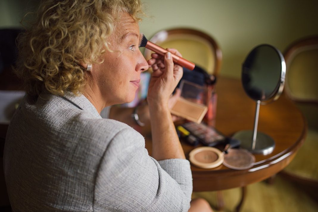 Femme appliquant du maquillage devant un miroir, illustration de la tendance des sourcils fins