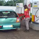 Une pompiste remplit le réservoir d’une voiture dans une station-service à Abidjan