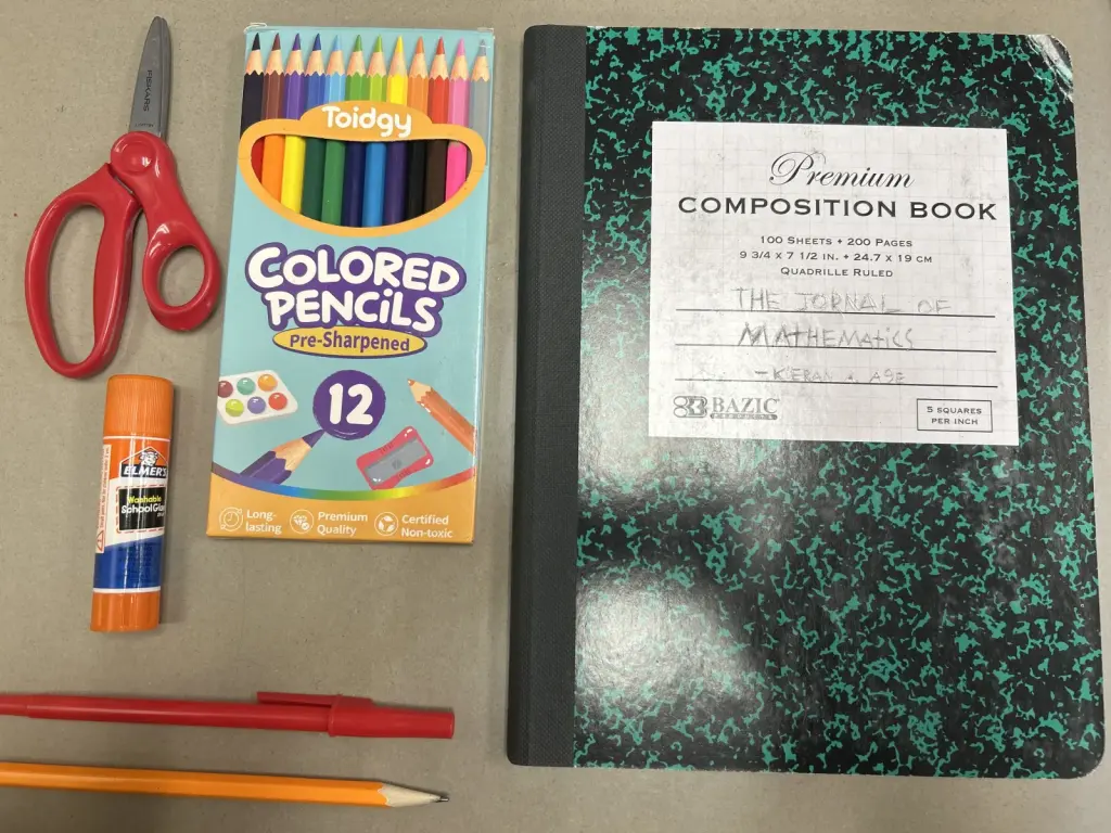 Cahier, crayons, stylos, colle et ciseaux parmi des fournitures scolaires