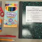 Cahier, crayons, stylos, colle et ciseaux parmi des fournitures scolaires